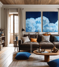 Living room with a brown sofa, blue and orange cushions, and two large cloud paintings on the wall.