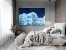 Modern bedroom with a large bed and two cloud-themed wall art pieces.