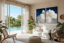 Modern living room with two cloud paintings, white sofa, plants, and a view of a pool and garden.