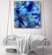 An abstract canvas wall art print with swirling shades of blue, navy, and silver, hanging in a mockup above a white hanging bed.