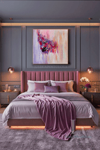 A modern bedroom featuring a bed dressed in dusty purple and lavender bedding, with a matching purple tufted headboard. Above the bed is a large, colorful abstract canvas painting.