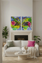 A modern living room setting featuring a two-panel abstract canvas art set hanging above a white fireplace. The vibrant paintings showcase a mix of blue, green, yellow, and pink brushstrokes.