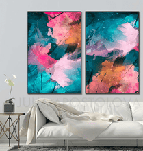 A pair of vertical framed canvas prints with abstract cosmic floral designs in pink, teal, and orange, displayed on a light gray wall above a white sofa in a modern living room setting.