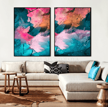 A pair of framed abstract canvas wall art prints hanging above a beige sectional sofa in a modern living room. The artwork features vibrant, fluid abstract patterns in pink, teal, orange, and purple with white paint splatters.