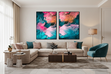A modern living room featuring a pair of large vertical abstract canvas wall art prints with vibrant pink, teal, and orange brushstrokes, hung above a beige sectional sofa.