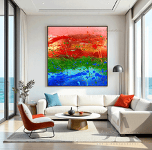Abstract colorful painting in a modern living room with white walls, a white sofa, a round table, and large windows with ocean view