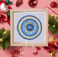 A colorful mandala-style design with concentric blue and white circles, surrounded by decorative Christmas ornaments and greenery on a pink background. Perfect greek evil eye art gift for protection, for Christmas, Valentine's Day, Birthday, and any occasion. 