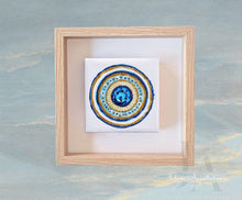 Framed artwork with a circular mandala design on a textured blue background