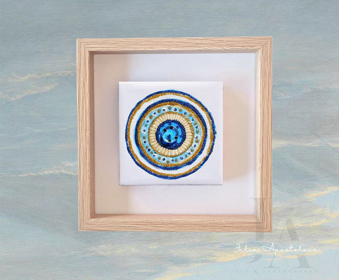 Framed artwork with a circular mandala design on a textured blue background