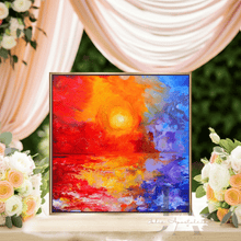 Colorful abstract painting on a table with floral arrangements and draped fabric in the background