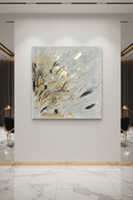 Abstract canvas wall art featuring textured brushstrokes in white, gold, gray, and black, displayed on a light gray wall in a modern interior setting.