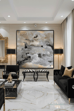 Modern living room with black furniture, marble floor, and abstract art on the wall with gold leaf, by artist Julia Apostolova. The painting's name is ''Milky Way'', features lots of real gold leaf, black and gray colors.