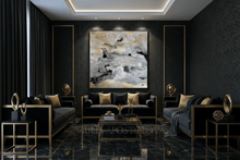 A luxury modern living room featuring a large abstract canvas painting with black, white, and gold brushstrokes, hung on a dark textured wall above a black sofa with gold accents.