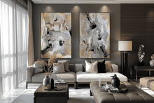 A modern living room featuring two large vertical abstract wall art prints with black, white, and gold marble-like patterns, hung above a gray sofa.