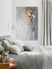 A modern interior space featuring a large abstract minimalist painting , hanging on the wall , in elegant bedroom. The painting is with soft gray silver hues, and some gold , white , copper rich textures, Hand-painted by artist Julia Apostolova. 