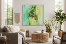 A large framed abstract painting with vibrant green, teal, yellow, and brown brushstrokes hangs on a white wall in a bright, modern living room with a beige sofa, round wicker coffee table, and potted plants.