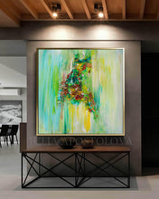 A large framed abstract painting with vibrant green, yellow, and brown brushstrokes, displayed on a gray wall above a console table in a modern interior setting.