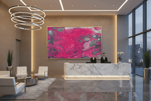 A large abstract wall art piece with vivid pink, magenta, and silver tones hangs in a modern lobby. The scene includes a marble reception desk, two people standing behind it, chairs, plants, and tall windows with a city view at dusk.