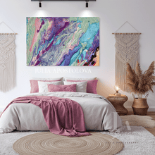 A colorful abstract canvas wall art print with swirling purple, blue, pink, and green patterns, displayed above a neatly made bed in a styled bedroom setting. The text 'JULIA APOSTOLOVA' is visible as a watermark across the center of the image.