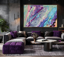 A large abstract canvas art print with swirling purple, teal, pink, and blue paint patterns, hanging on a dark gray wall above a modern gray sectional sofa with purple pillows.