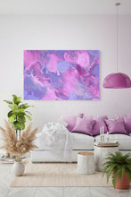 An abstract canvas wall art print featuring swirling purple and pink paint patterns, displayed in a modern living room setting above a white sofa with purple pillows.