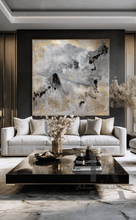 Modern Living room with large canvas in gray gold black and real gold leaf beautiful details, that shimmer under the different lighting, hanging over light colored couch , on dark gray wall, creating a glam atmosphere. The room features low modern coffee table and decorative elements, like vases candles and book. 
