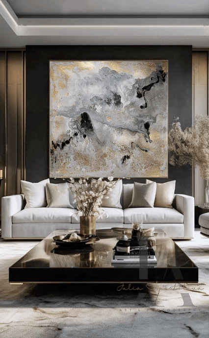 Modern Living room with large canvas in gray gold black and real gold leaf beautiful details, that shimmer under the different lighting, hanging over light colored couch , on dark gray wall, creating a glam atmosphere. The room features low modern coffee table and decorative elements, like vases candles and book. 