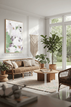 Living room with wicker sofa, floral painting, round wooden coffee table, and large windows with garden view.