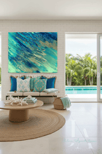 Modern living room with ocean abstract artwork, seating area, coastal accents, and pool view.
