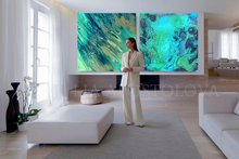 Woman standing in a modern living room with teal abstract art on the wall by artist Julia Apostolova