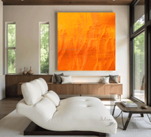A large orange minimalist painting , displayed on white wall in a modern living room with a white sofa , a black low coffee table and a large window overlooking a natural landscape , creating a warm and inviting atmosphere