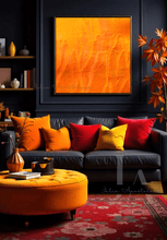 A modern living room with a large abstract orange painting on the wall featuring shades of orange and yellow. The room has a dark color scheme with a large white modern dark leather sofa, pink orange and red pillows, a low yellow coffee table, and a textured area rug on the floor. 