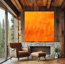 A large orange minimalist painting , displayed on wooden wall over fireplace in a rustic sale living room with a large window overlooking a natural landscape , creating a warm and inviting atmosphere