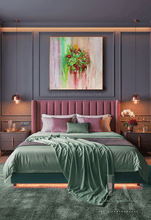 A styled bedroom interior featuring a bed dressed in sage green bedding and purple pillows, set against a dark gray paneled wall with a colorful abstract floral painting above the headboard.