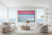 Modern living room with a large abstract painting on the wall with ocean scene, surrounded with white furniture, and a view of the ocean.