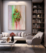 A large vertical abstract canvas painting  by artist Julia Apostolova, with vibrant green, pink, red, and yellow brushstrokes hangs on a light gray wall above a white sofa in a modern living room setting.