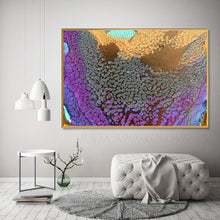 Large framed abstract wall art hanging above a tufted bench in a styled living room. The artwork features swirling purple, blue, gold, and silver tones with a textured, crackled surface and a thin gold frame.