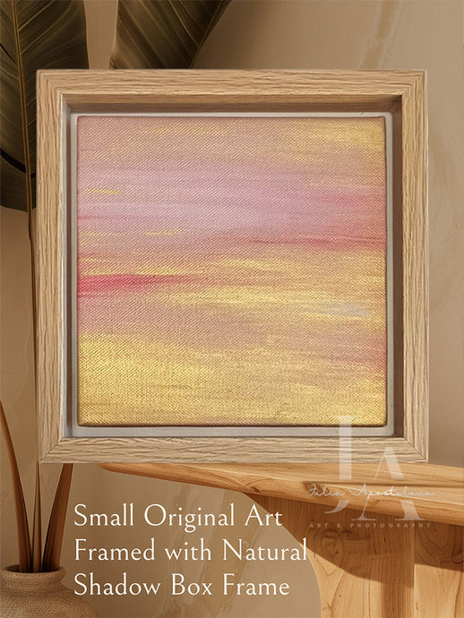 A pastel minimalist landscape with a rose pink, and metallic gold, framed in a wooden frame.