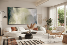Modern living room with a white sofa, round black coffee table, and sage green abstract painting on the wall.