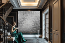 Woman in a green dress sitting on a staircase in a stylish interior setting with oversize original 3d silver painting, by artist Julia Apostolova.