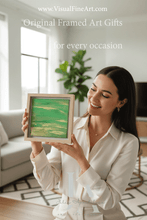 Woman holding an original  framed green painting in a bright living room