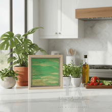Kitchen counter with plants, a framed green artwork, and kitchen items.