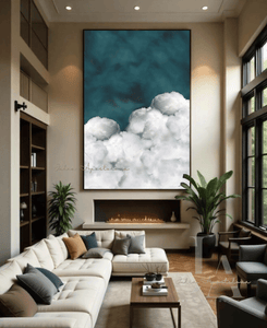 A cozy and inviting modern living room with a large cloud painting, hanging over fireplace. The room features light colored walls, a large sectional white sofa,  and large windows that provide a scenic view of the outdoors. The overall atmosphere is warm and cosy, creating a comfortable and relaxing environment