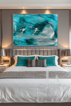 A large framed abstract painting with swirling turquoise, teal, white, and silver brushstrokes hangs above a neatly made bed in a modern bedroom. The room has gray walls, a tufted headboard, white bedding, and two bedside lamps.