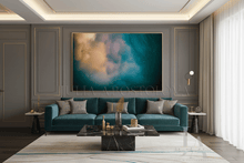 A large framed abstract wall art print hangs above a teal sofa in a modern living room. The artwork features swirling teal, blue, cream, and gold tones with small star-like specks.