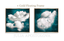 Two framed cloud art prints displayed side by side on a white background, with the text '+ Gold Floating Frame' above and 'JULIA APOSTOLOVA' below. The prints show white clouds against a deep teal and black cosmic background, each enclosed in a thin gold frame.