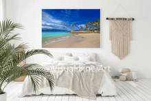 Beach scene wall art in a bedroom with a bed and plant.