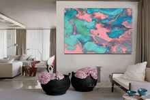 A large abstract canvas wall art print with swirling pink, teal, and turquoise paint patterns, displayed in a modern living room setting above two black planters filled with pink flowers.
