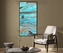An abstract canvas wall art print by Artist Julia Apostolova , featuring turquoise, teal, gray, and black fluid patterns, displayed in a modern living room setting above a gray stone coffee table and next to a white armchair.