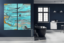 A two-panel abstract wall art set by artist Julia Apostolova , with swirling turquoise, teal, gray, black, and orange fluid patterns, displayed in a modern bathroom setting next to a black freestanding tub.